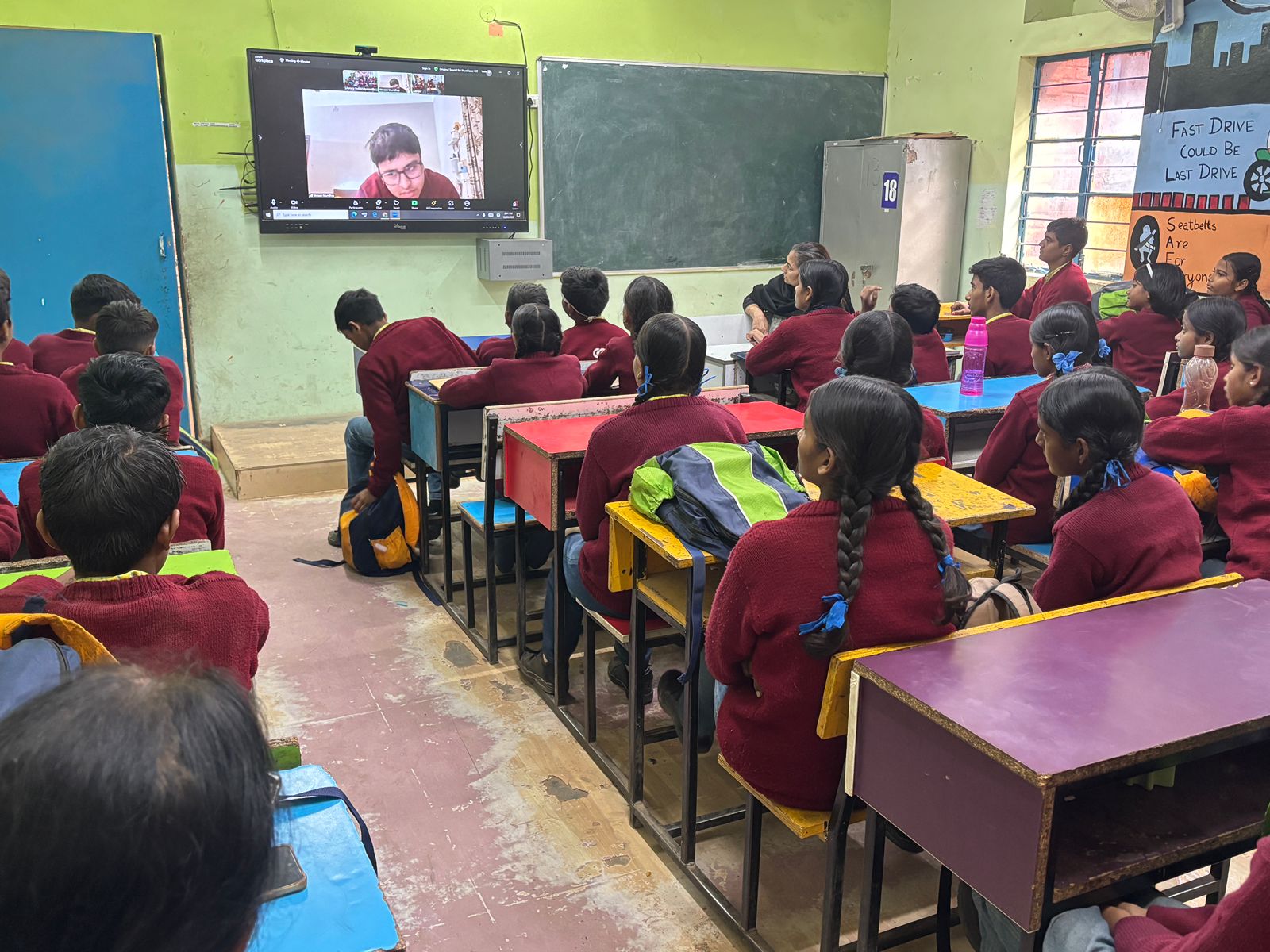 Wide classroom view with Vevaan presenting live on the screen at the front