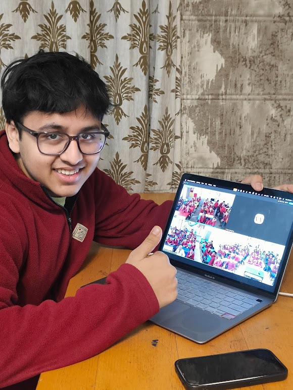 Vevaan Mundhra at his laptop, pointing at a group photo on the screen showing the 150+ students FinLight has worked with